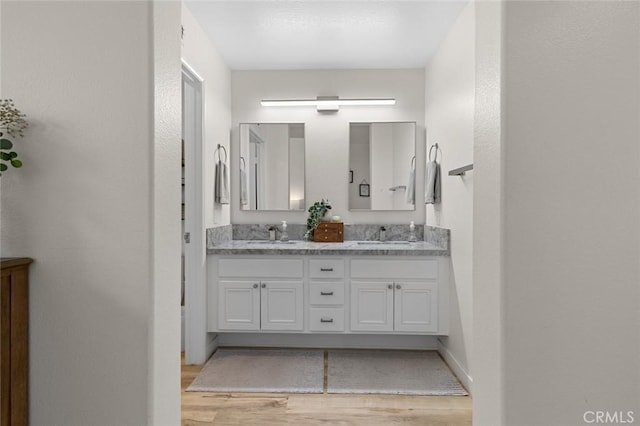 full bath featuring double vanity, wood finished floors, and a sink