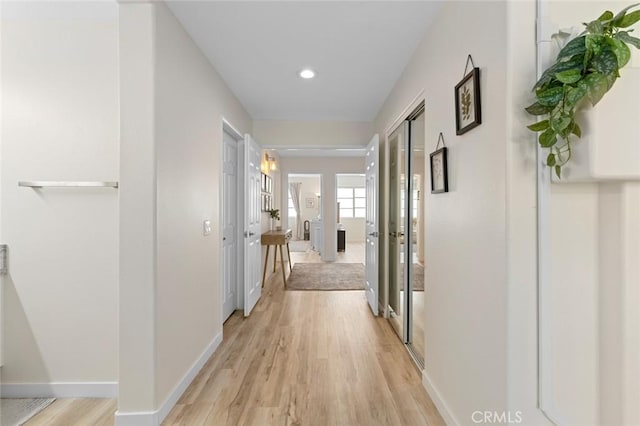 hall featuring recessed lighting, baseboards, and light wood-style flooring