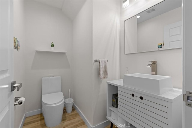 half bath featuring visible vents, baseboards, toilet, wood finished floors, and vanity