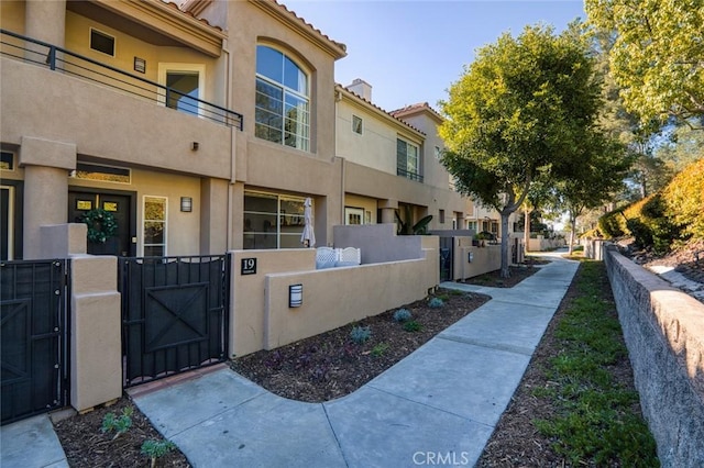 exterior space with stucco siding, a fenced front yard, and a gate