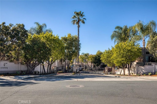 view of road with a gated entry, sidewalks, curbs, and a gate