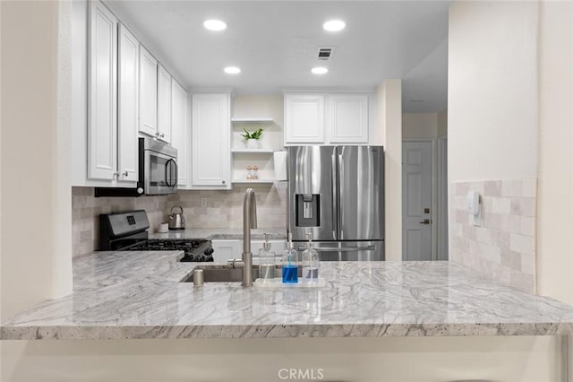 kitchen featuring visible vents, a sink, appliances with stainless steel finishes, a peninsula, and open shelves