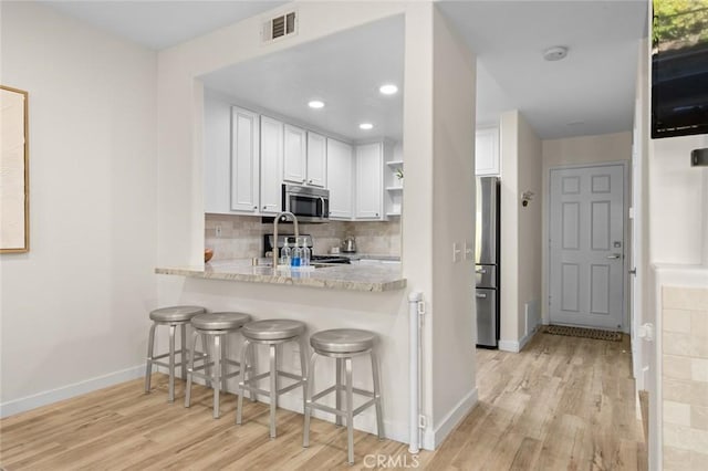 kitchen with visible vents, open shelves, tasteful backsplash, white cabinetry, and stainless steel appliances