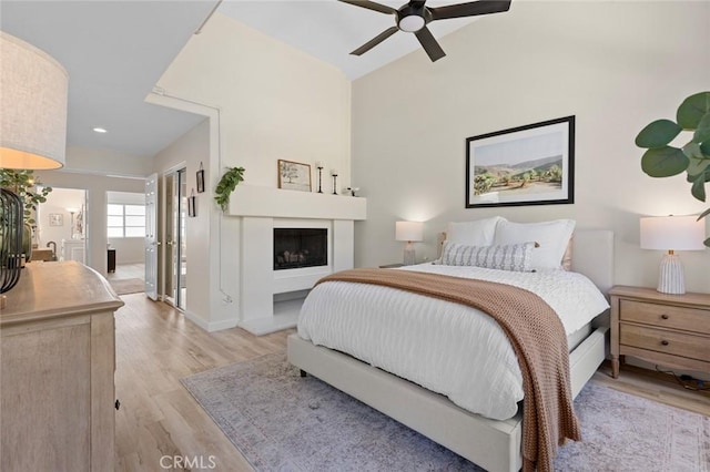 bedroom featuring ceiling fan, a fireplace, baseboards, and light wood-style floors