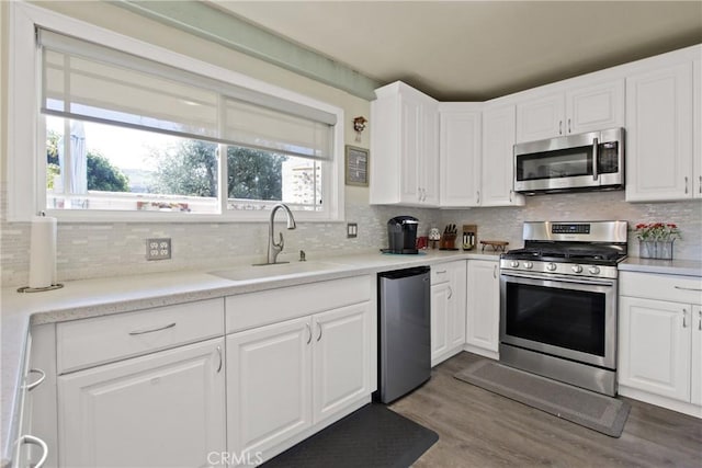 kitchen featuring dark wood-style flooring, white cabinets, stainless steel appliances, and a sink