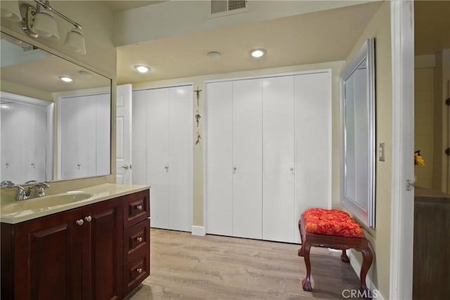 bathroom with recessed lighting, visible vents, wood finished floors, and vanity