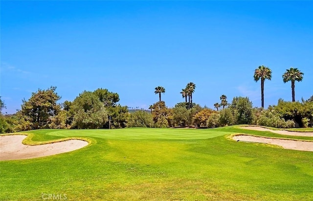 view of property's community featuring view of golf course and a lawn