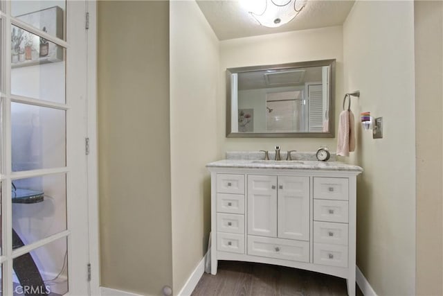 full bath featuring vanity, baseboards, and wood finished floors