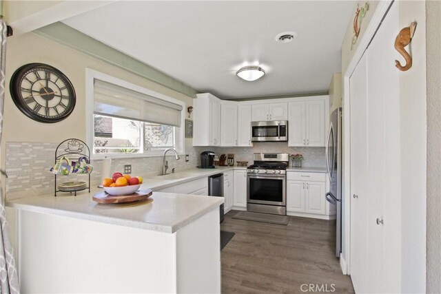 kitchen featuring visible vents, appliances with stainless steel finishes, a peninsula, white cabinets, and a sink