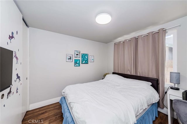 bedroom with dark wood-type flooring and baseboards