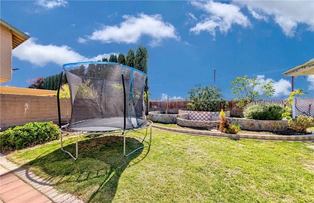 view of yard with a trampoline and a fenced backyard