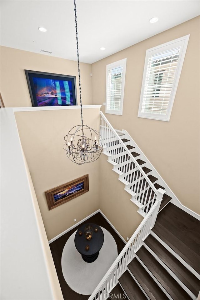 stairway with visible vents, a notable chandelier, wood finished floors, recessed lighting, and baseboards