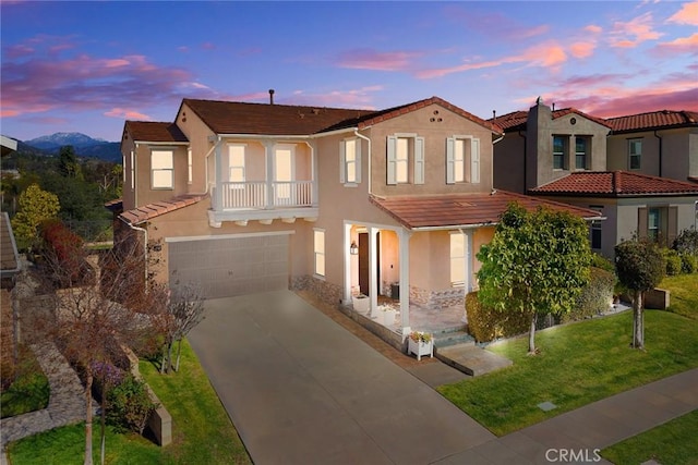 mediterranean / spanish home featuring a tile roof, concrete driveway, a front yard, stucco siding, and a garage