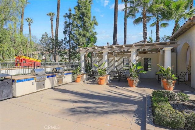 view of patio / terrace with fence, playground community, exterior kitchen, a pergola, and grilling area