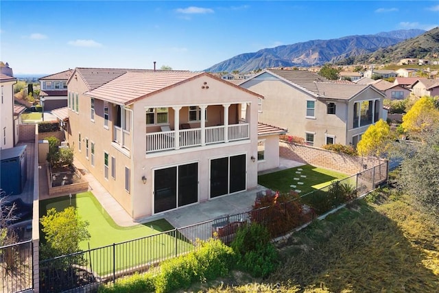 back of house featuring stucco siding, a lawn, a fenced backyard, a balcony, and a patio