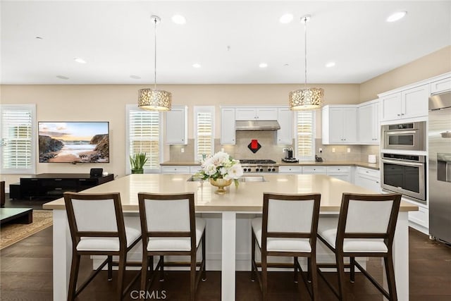 kitchen with under cabinet range hood, white cabinets, light countertops, and backsplash