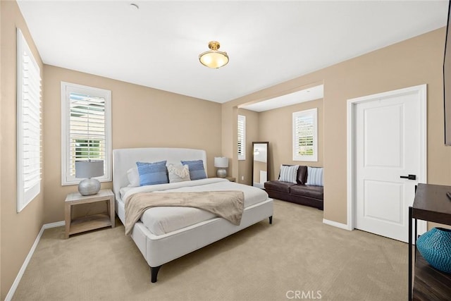 bedroom with light colored carpet and baseboards