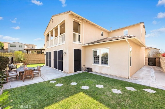 back of property with stucco siding, a lawn, a patio, and fence