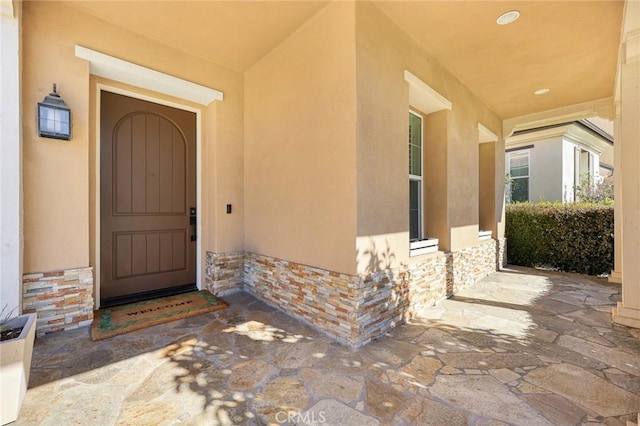 property entrance featuring stone siding and stucco siding