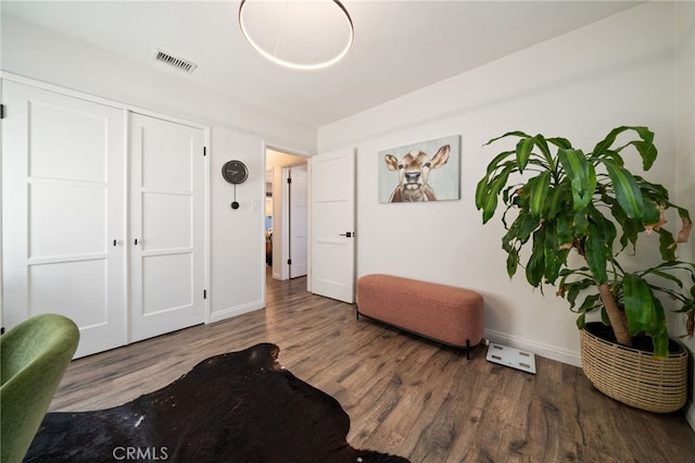 living area featuring visible vents, baseboards, and wood finished floors