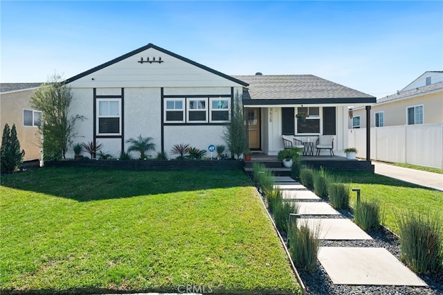 view of front of house featuring stucco siding, covered porch, a front lawn, and fence