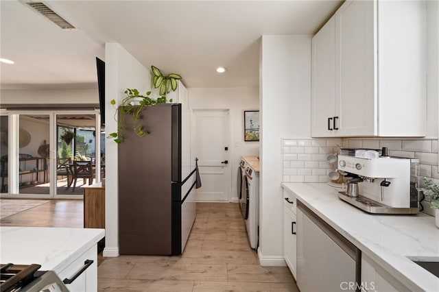 kitchen with visible vents, tasteful backsplash, white cabinetry, freestanding refrigerator, and separate washer and dryer