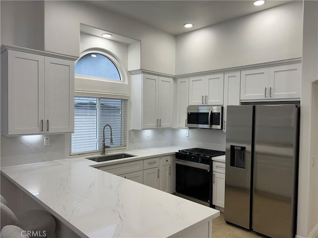 kitchen with a breakfast bar, a peninsula, a sink, decorative backsplash, and appliances with stainless steel finishes