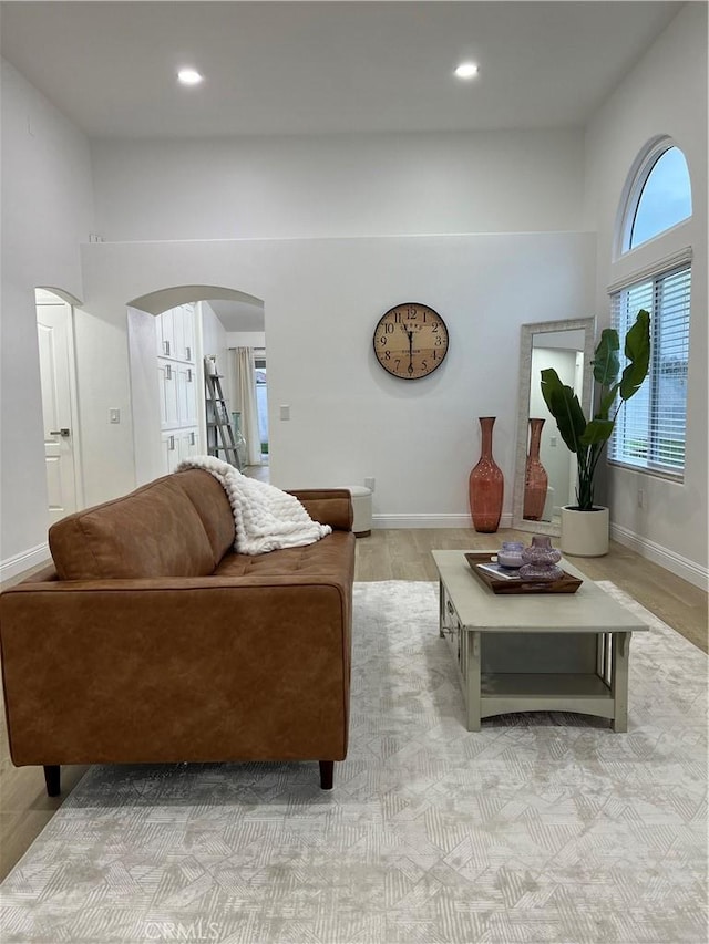 living area featuring arched walkways, recessed lighting, and baseboards