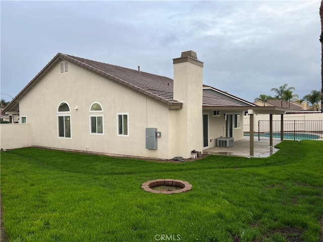 rear view of house with stucco siding, a patio, a yard, and fence