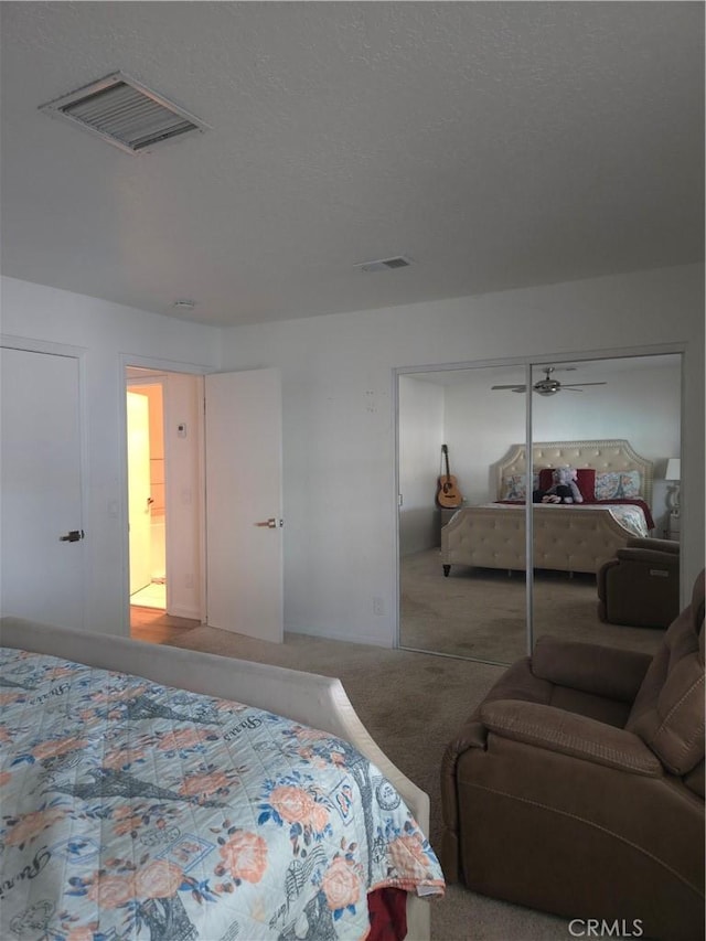 carpeted bedroom with visible vents, a closet, and a textured ceiling