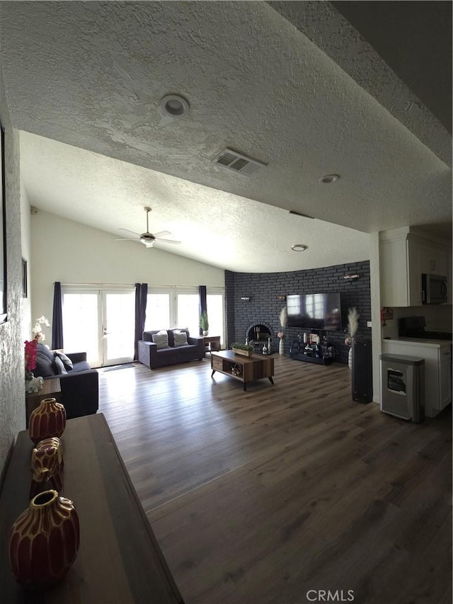 living area featuring visible vents, lofted ceiling, dark wood-type flooring, and a fireplace