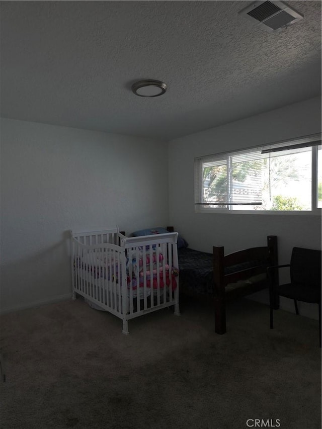 bedroom with visible vents, carpet flooring, and a textured ceiling