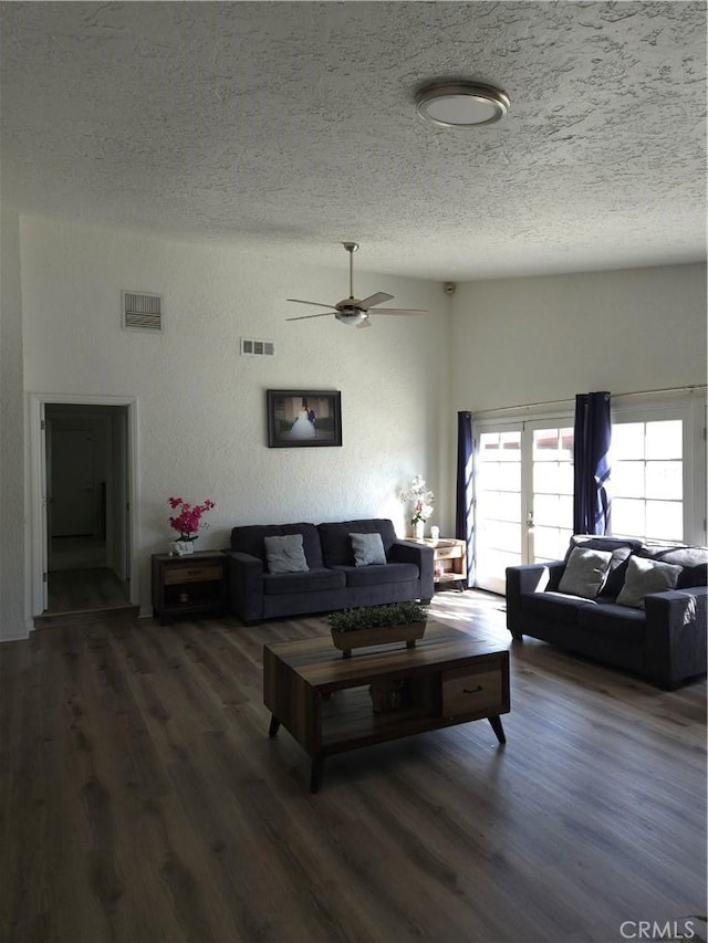 living room with visible vents, a textured ceiling, a ceiling fan, and wood finished floors