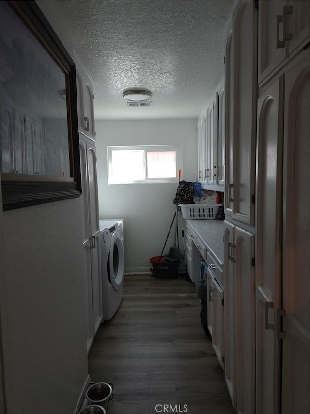 laundry area with washing machine and clothes dryer, visible vents, laundry area, wood finished floors, and a textured ceiling