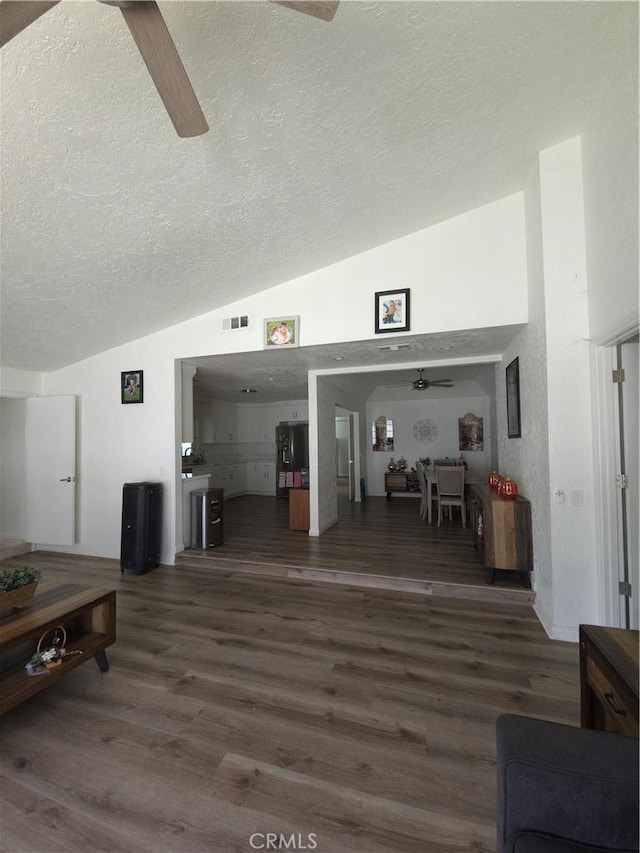 interior space featuring visible vents, ceiling fan, vaulted ceiling, wood finished floors, and a textured ceiling