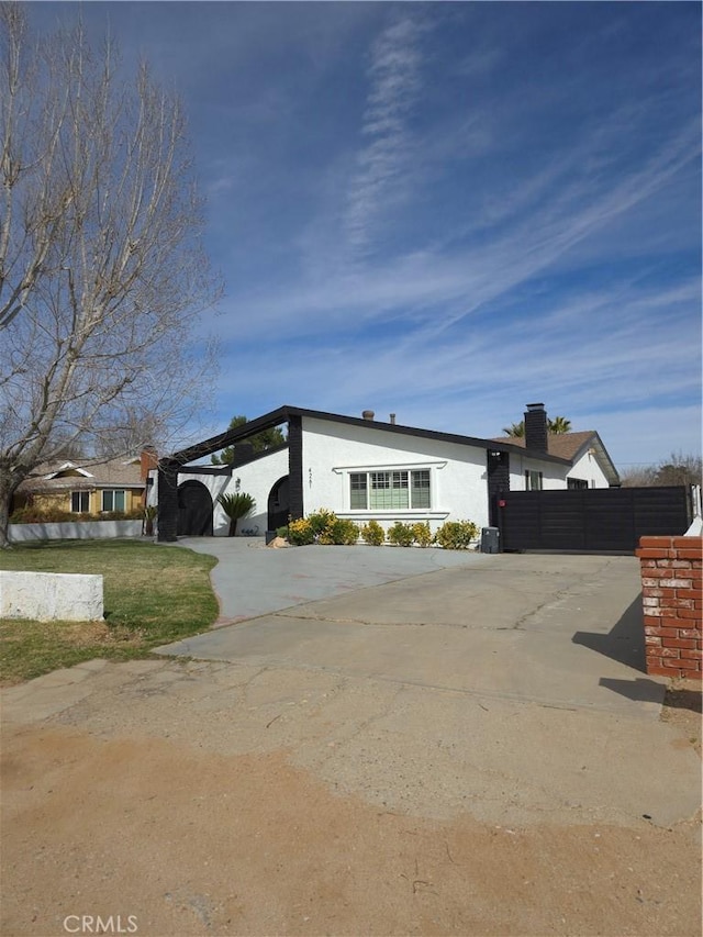 view of front of house featuring stucco siding, driveway, and fence