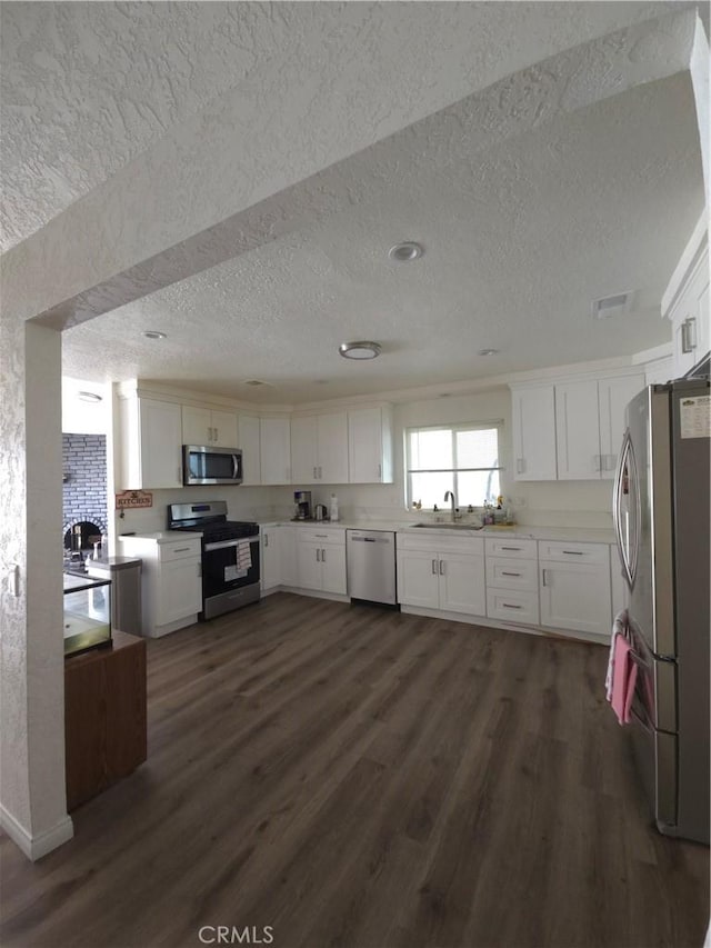 kitchen with white cabinets, stainless steel appliances, and dark wood-type flooring