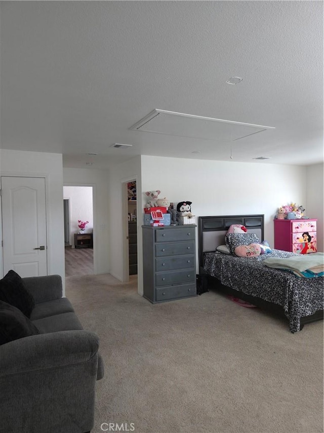 carpeted bedroom featuring visible vents, a textured ceiling, and attic access