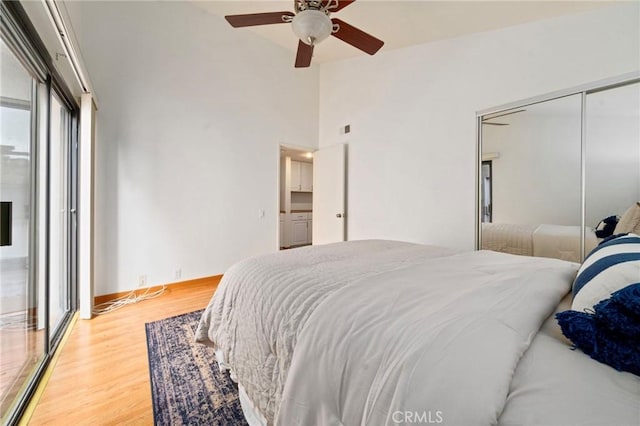 bedroom featuring baseboards, wood finished floors, a closet, high vaulted ceiling, and a ceiling fan