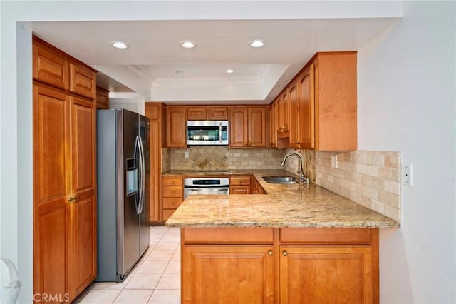 kitchen featuring tasteful backsplash, light tile patterned floors, appliances with stainless steel finishes, a peninsula, and a sink