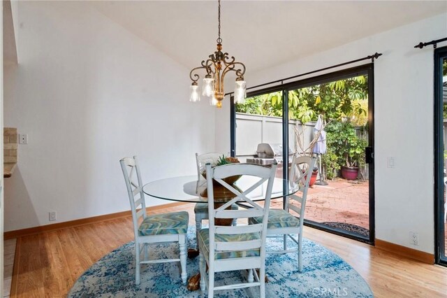 dining area with lofted ceiling, baseboards, light wood finished floors, and a chandelier