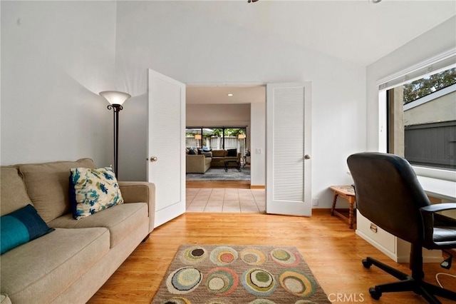 home office with baseboards, light wood-style floors, and high vaulted ceiling