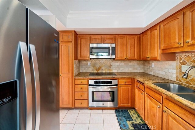 kitchen with a sink, brown cabinets, appliances with stainless steel finishes, and ornamental molding