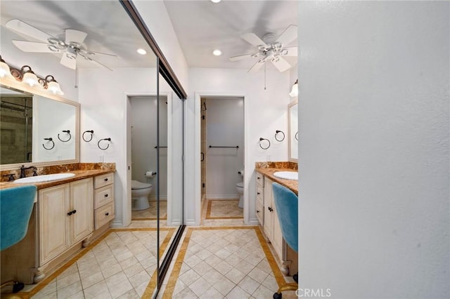 bathroom featuring toilet, two vanities, a ceiling fan, a sink, and tile patterned flooring