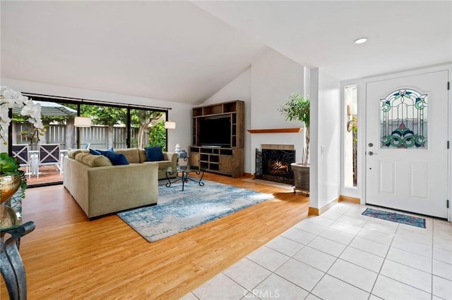 entrance foyer with vaulted ceiling, a fireplace with flush hearth, baseboards, and light wood finished floors