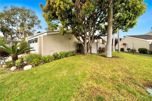 exterior space featuring a front lawn, an attached garage, and stucco siding