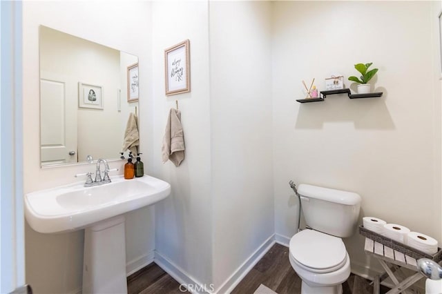 bathroom with a sink, toilet, baseboards, and wood finished floors