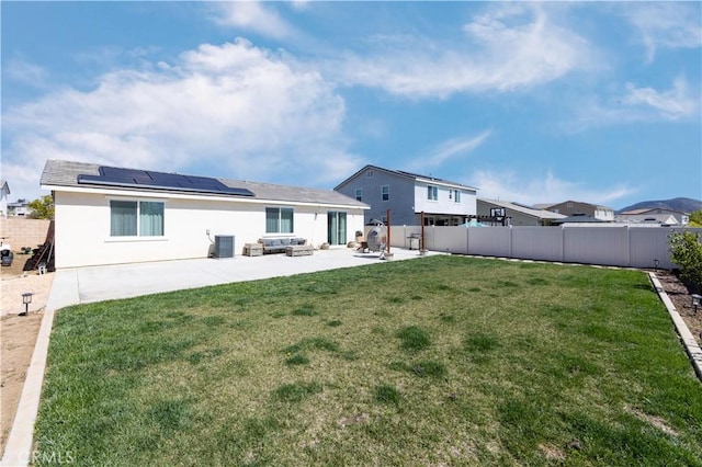 back of house with a patio, a yard, a fenced backyard, stucco siding, and roof mounted solar panels