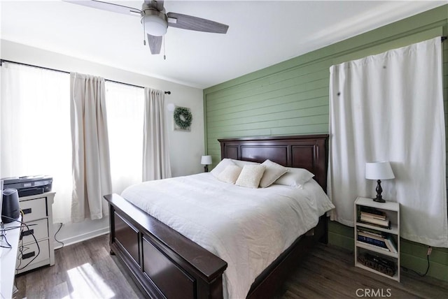 bedroom featuring ceiling fan, wooden walls, and dark wood-style floors