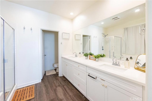 full bath with a sink, toilet, wood finished floors, and a shower stall